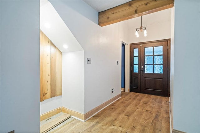 entrance foyer featuring beamed ceiling, an inviting chandelier, and light hardwood / wood-style floors