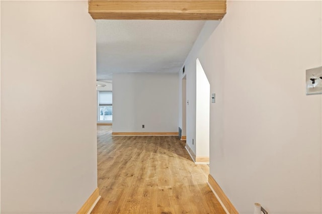 hallway with light hardwood / wood-style flooring and beam ceiling