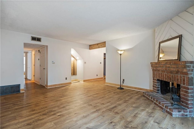 unfurnished living room featuring a brick fireplace and wood-type flooring