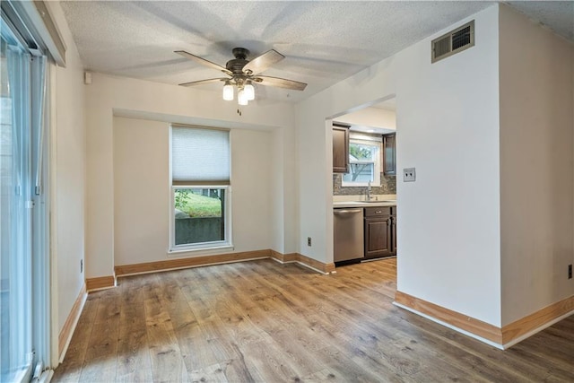 unfurnished room featuring a textured ceiling, ceiling fan, light hardwood / wood-style flooring, and sink