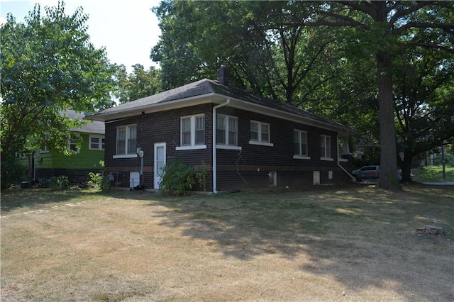 view of side of home featuring a yard, brick siding, and a chimney