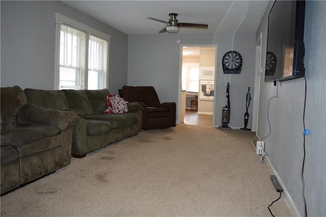 carpeted living area featuring baseboards and a ceiling fan