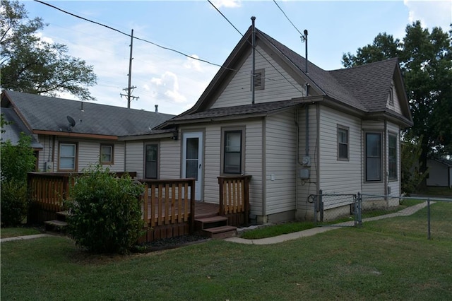 view of front of home with a deck, a shingled roof, fence, a gate, and a front yard