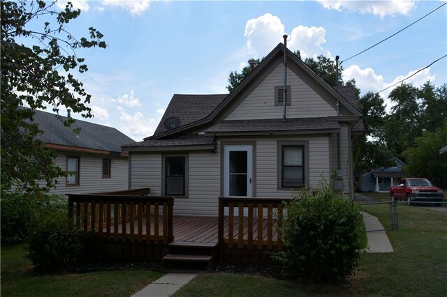 bungalow-style home featuring a front yard and a wooden deck