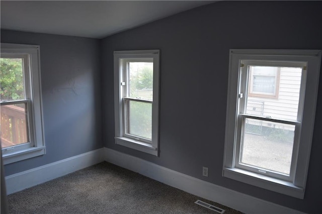 empty room featuring baseboards, visible vents, vaulted ceiling, and carpet flooring