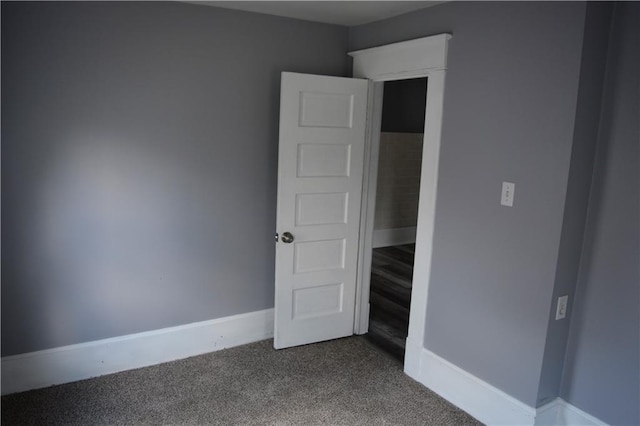 unfurnished bedroom featuring dark carpet and baseboards