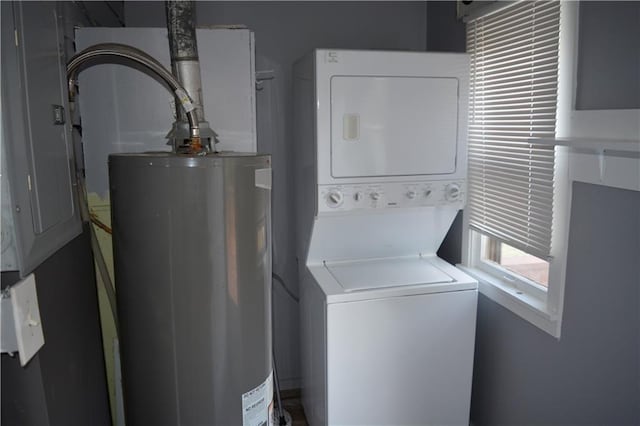 washroom featuring water heater, laundry area, and stacked washer / dryer