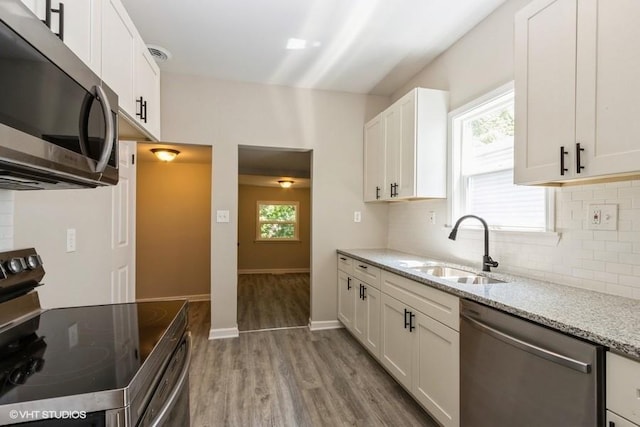 kitchen featuring plenty of natural light, stainless steel appliances, sink, and light stone countertops