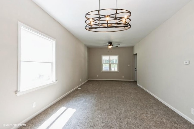 empty room with carpet and ceiling fan with notable chandelier