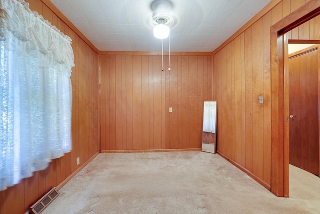 carpeted spare room with wooden walls