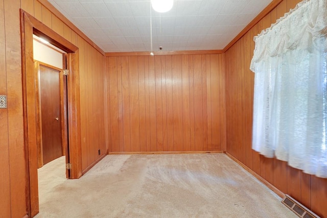 carpeted spare room featuring wood walls