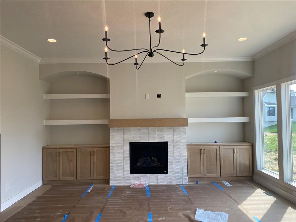 2914 NE 102nd St, Kansas City, MO 64155 - unfurnished living room with baseboards, built in shelves, a chandelier, and crown molding