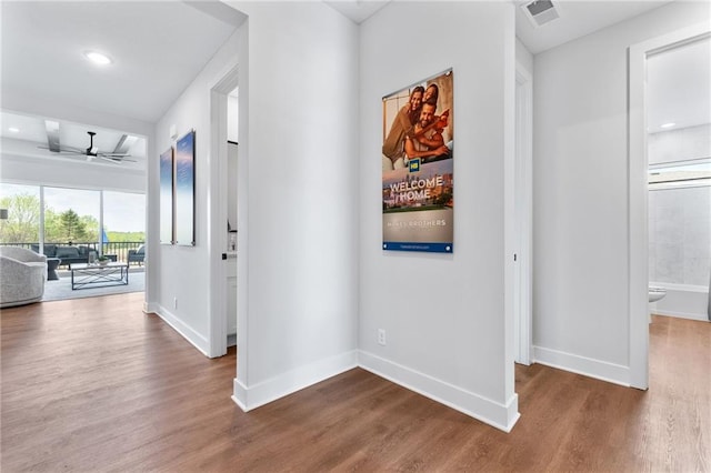 hallway featuring visible vents, baseboards, and dark wood finished floors