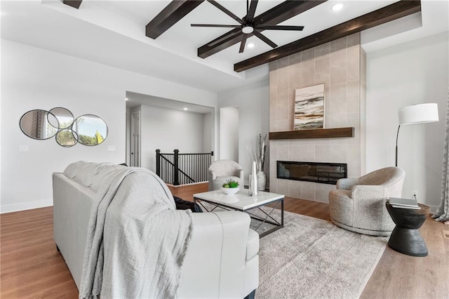 living area with a tile fireplace, recessed lighting, wood finished floors, baseboards, and beam ceiling