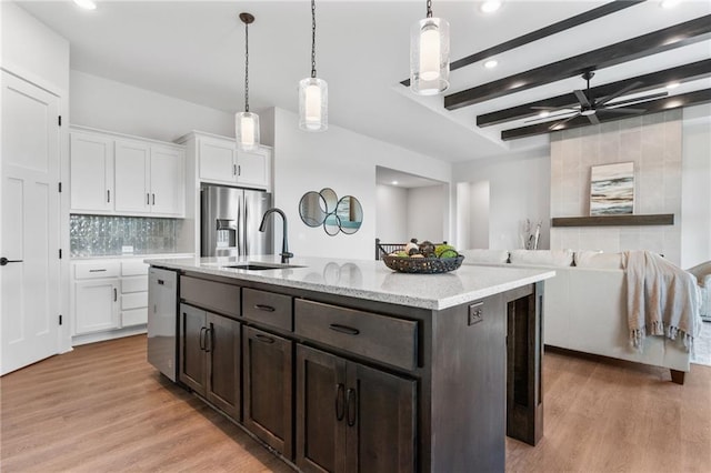 kitchen featuring light wood-style flooring, white cabinets, appliances with stainless steel finishes, beam ceiling, and decorative backsplash