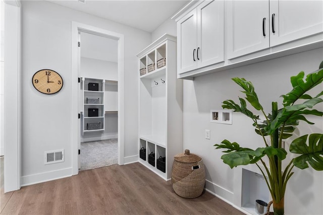 mudroom featuring baseboards, visible vents, and wood finished floors