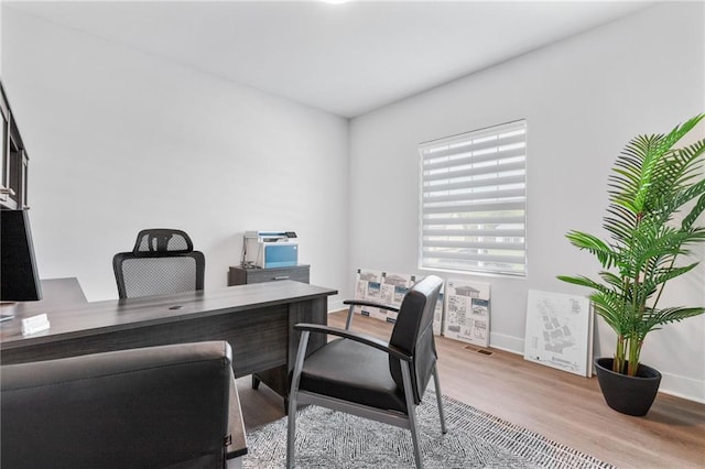 office area with light wood finished floors, visible vents, and baseboards