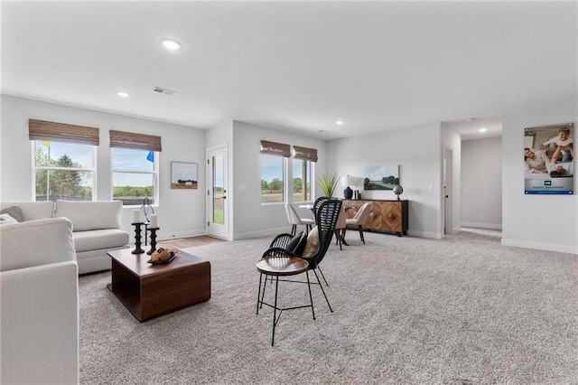 living area with recessed lighting, light colored carpet, visible vents, and baseboards