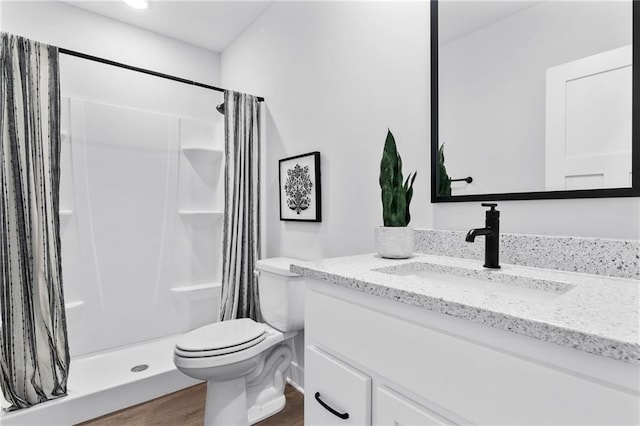 bathroom featuring toilet, a stall shower, wood finished floors, and vanity