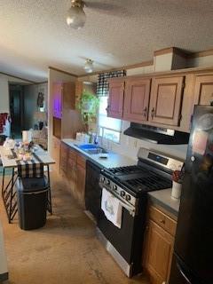 kitchen with black appliances, a textured ceiling, sink, and range hood