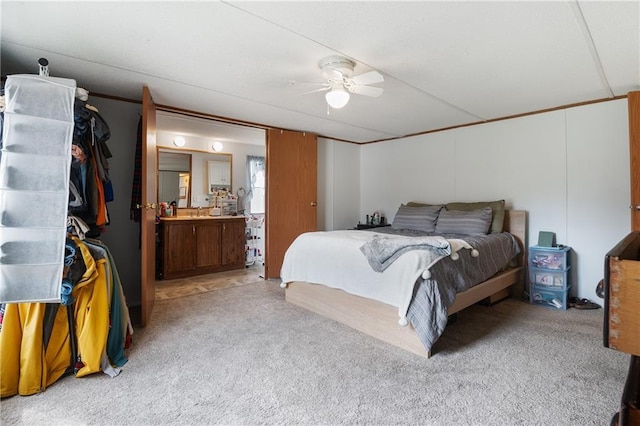 bedroom featuring light carpet, ceiling fan, and connected bathroom