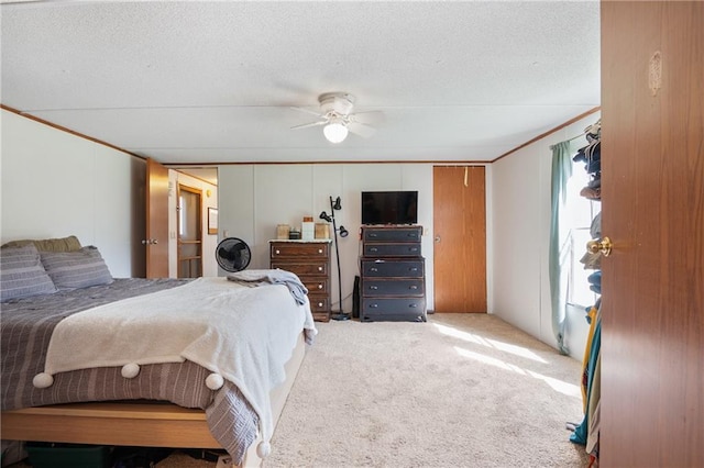 carpeted bedroom featuring a ceiling fan, crown molding, and a textured ceiling