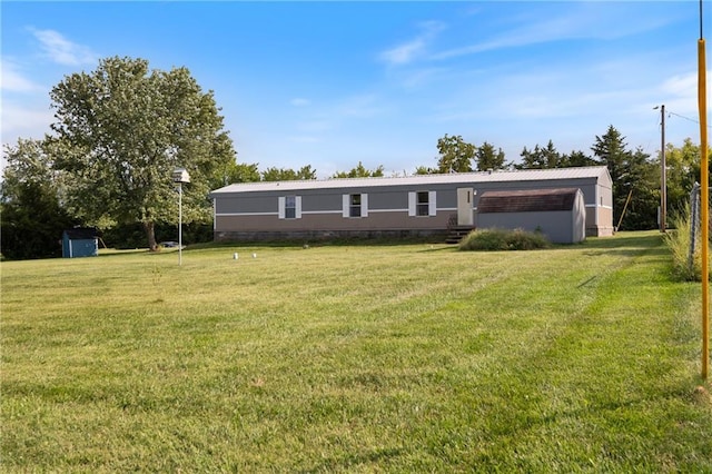 manufactured / mobile home with crawl space, metal roof, an outbuilding, and a front yard