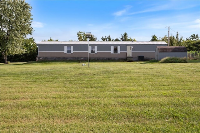 rear view of property featuring central air condition unit, metal roof, and a lawn