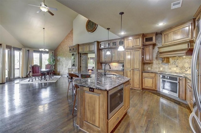 kitchen with dark hardwood / wood-style flooring, a center island with sink, stainless steel appliances, and a breakfast bar