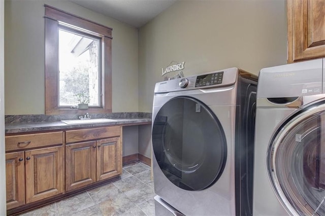 clothes washing area featuring washer and clothes dryer, cabinets, and sink