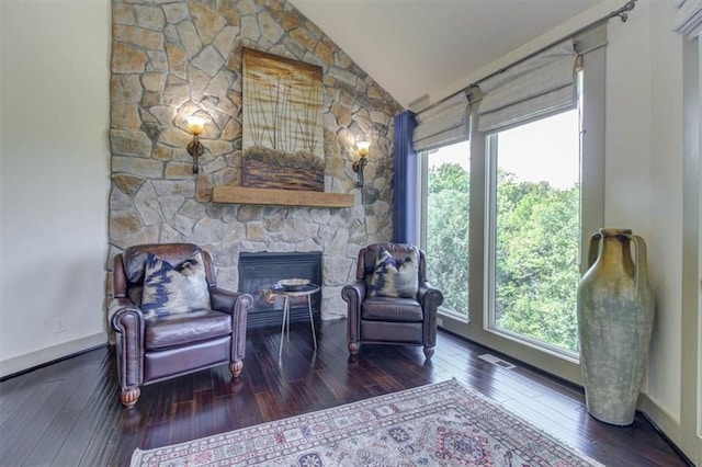 living area with a fireplace, vaulted ceiling, a wealth of natural light, and dark wood-type flooring