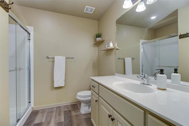 bathroom featuring a shower with shower door, toilet, wood-type flooring, and vanity