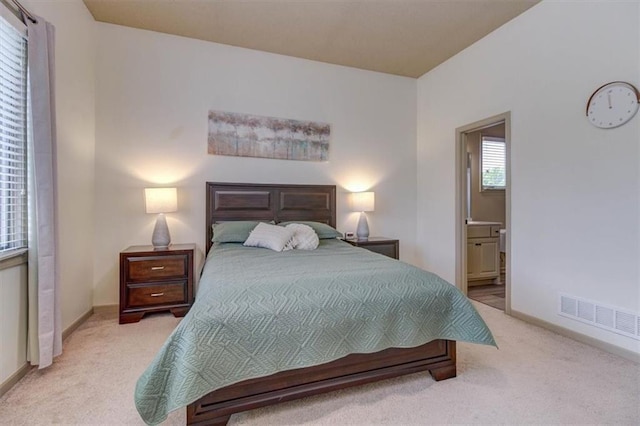 bedroom featuring light colored carpet and connected bathroom