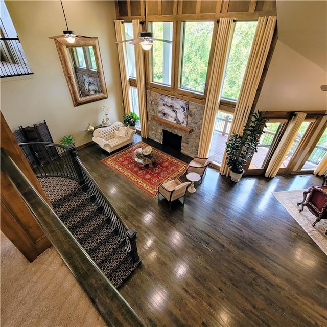 living room with a fireplace, dark hardwood / wood-style flooring, a towering ceiling, and ceiling fan