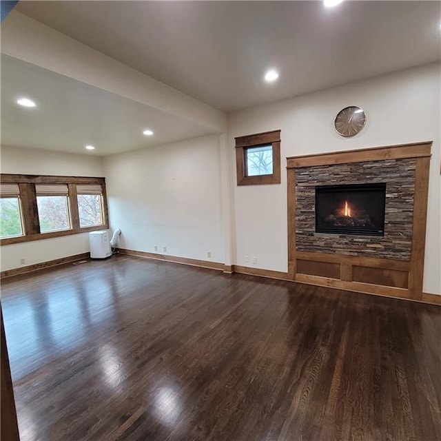 unfurnished living room with a fireplace, dark hardwood / wood-style flooring, and a healthy amount of sunlight