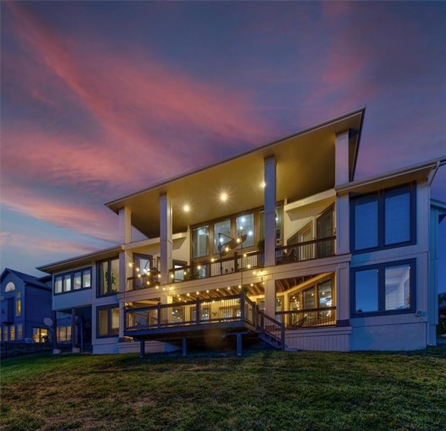 back house at dusk featuring a lawn