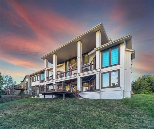 back house at dusk with a lawn and a balcony