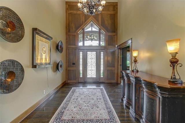 foyer entrance featuring a towering ceiling, dark hardwood / wood-style floors, and a notable chandelier