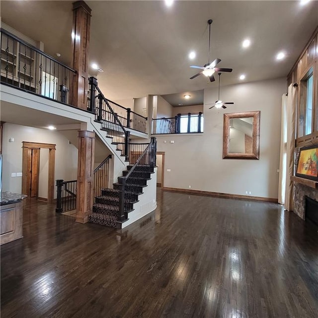 living room with a high ceiling, dark hardwood / wood-style flooring, and ceiling fan