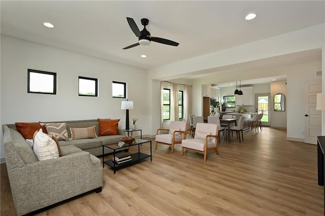 living room featuring light hardwood / wood-style floors, ceiling fan, and a wealth of natural light