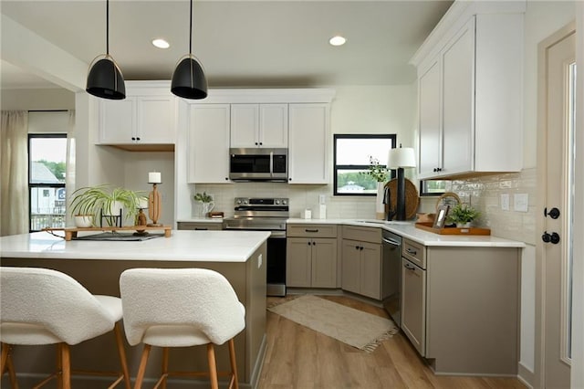 kitchen with pendant lighting, appliances with stainless steel finishes, white cabinetry, and a wealth of natural light