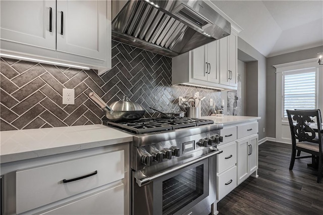 kitchen featuring white cabinets, backsplash, custom range hood, stainless steel stove, and lofted ceiling