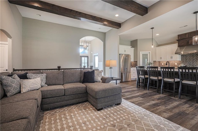 living room featuring a towering ceiling, dark wood-type flooring, and beam ceiling