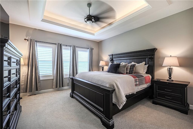 carpeted bedroom featuring a tray ceiling and ceiling fan