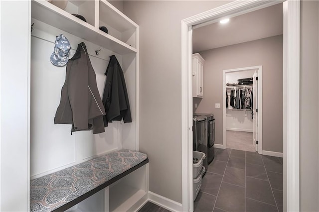 mudroom featuring washing machine and clothes dryer and dark tile patterned floors