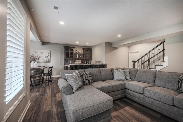 living room featuring bar area and dark wood-type flooring