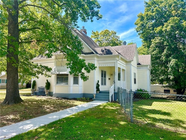 view of front facade with roof with shingles, a chimney, fence, and a front yard