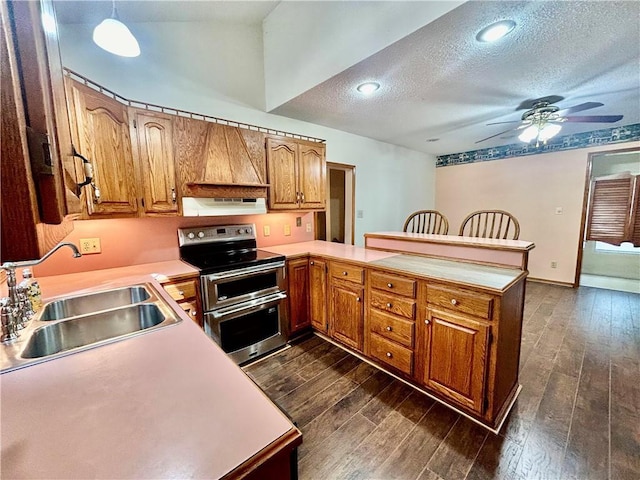 kitchen featuring range with two ovens, dark wood-style flooring, a sink, a peninsula, and exhaust hood