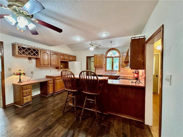 kitchen with a textured ceiling, dark hardwood / wood-style floors, kitchen peninsula, ceiling fan, and white refrigerator