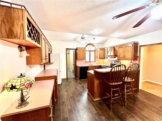 kitchen featuring a textured ceiling, dark hardwood / wood-style floors, a breakfast bar, stainless steel range with electric stovetop, and ceiling fan